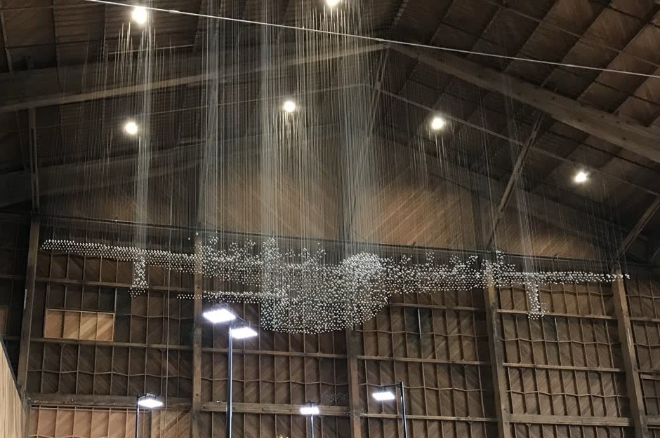 Suspended sculpture of stainless steel float balls hanging in a timber barn studio